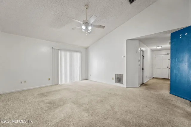 a view of an empty room with a chandelier fan