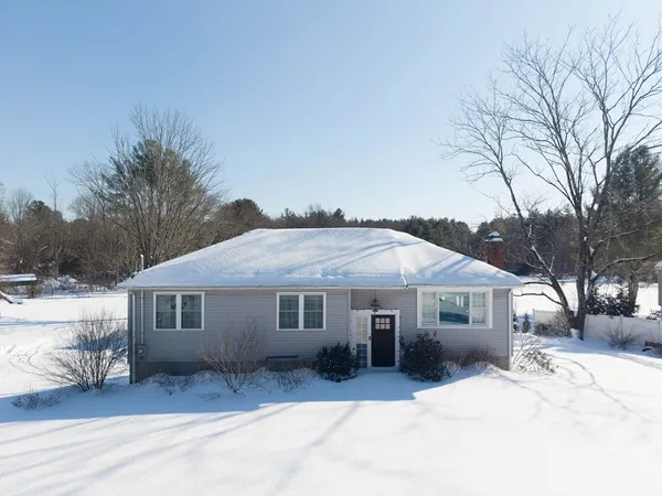 a front view of a house with a yard covered in snow