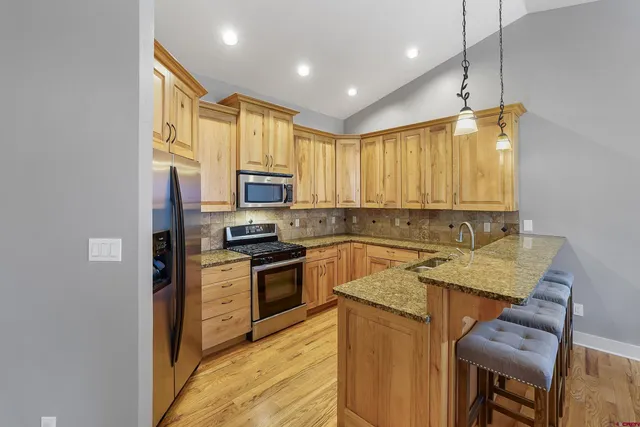 a kitchen with stainless steel appliances granite countertop wooden cabinets a stove top oven a sink and dishwasher