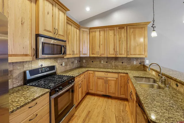 a kitchen with stainless steel appliances granite countertop a stove a sink and a microwave