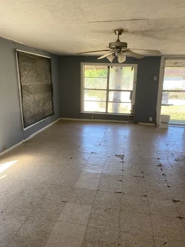 an empty room with windows and fireplace