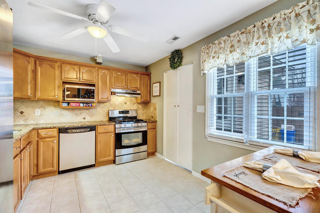 39 Kingsley Way Freehold, NJ 07728 - Photo 10 of 24 a kitchen with stainless steel appliances granite countertop a stove top oven a sink dishwasher a refrigerator and a dining table with wooden floor