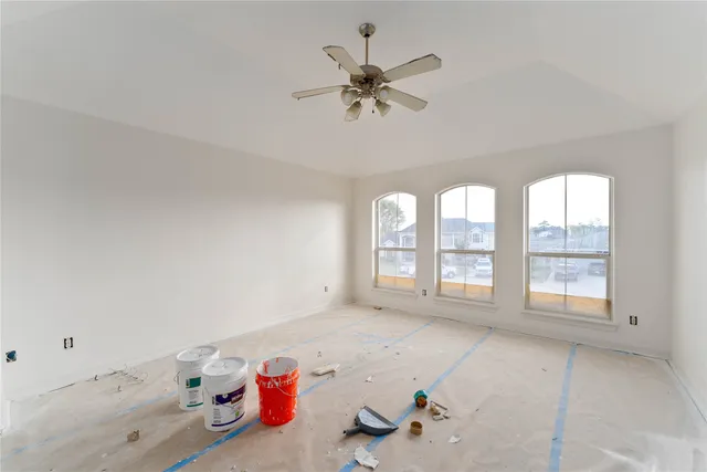 an empty room with windows and fan