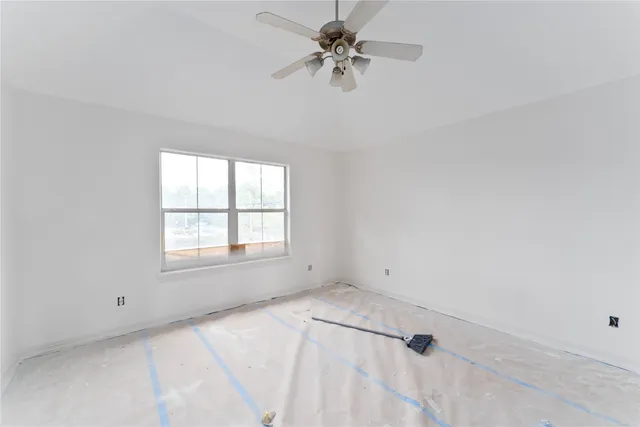 an empty room with a window and a fan