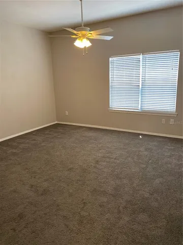 an empty room with windows and chandelier fan