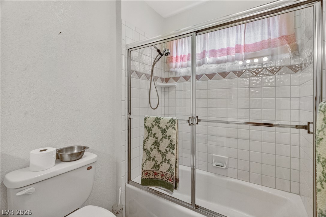 2055 Cholla Way Laughlin, NV 89029 - Photo 25 of 87 White subway tiles elegantly line the walls around a classic bathtub, encased by a sleek glass shower enclosure.