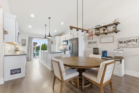 a kitchen with stainless steel appliances kitchen island granite countertop a dining table chairs and white cabinets