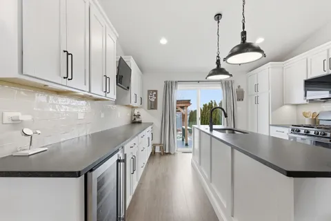 a kitchen with kitchen island granite countertop a sink a counter space appliances and cabinets