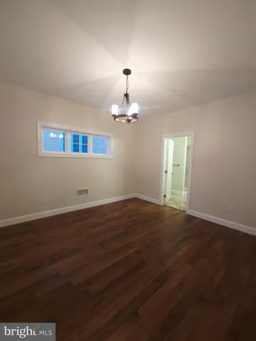 an empty room with wooden floor chandelier and windows