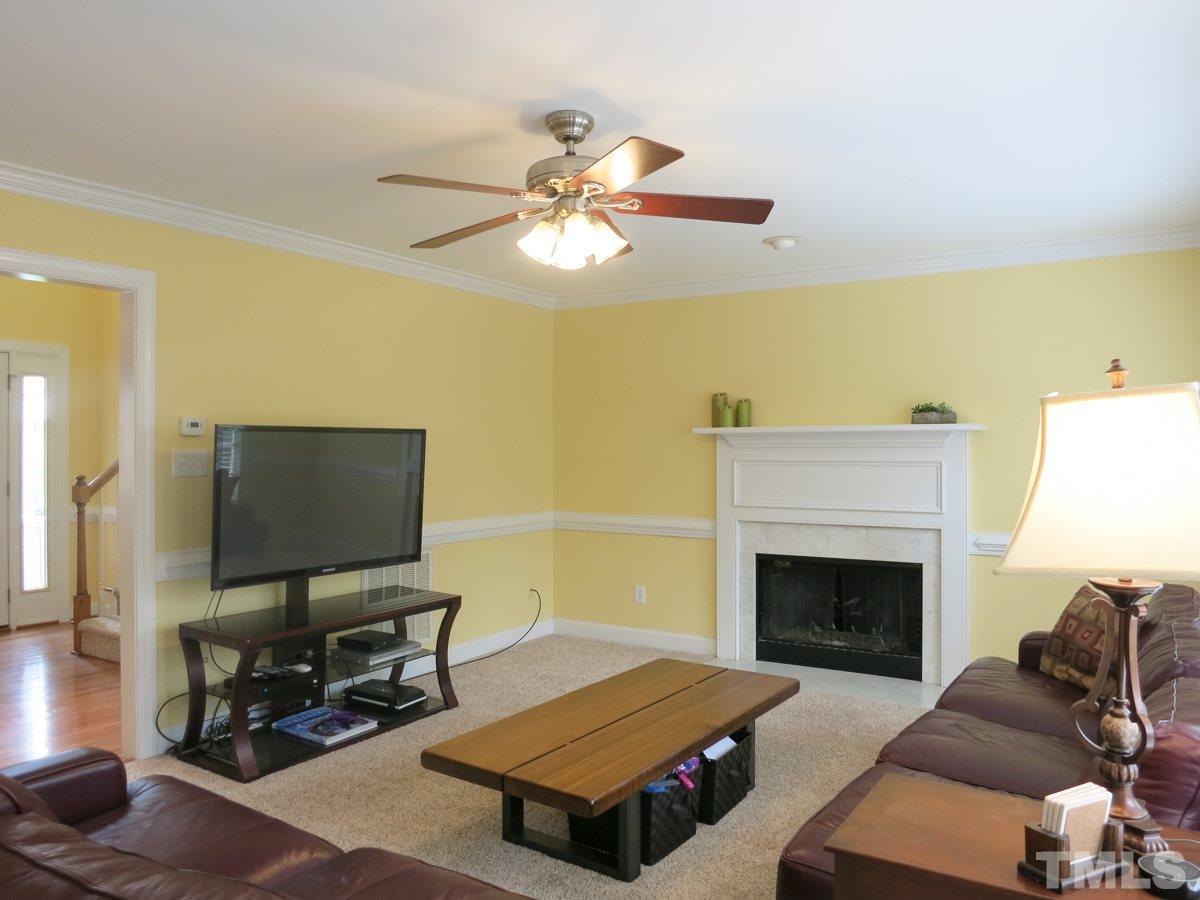 9305 Dawnshire Road Raleigh, NC 27615 - Photo 6 of 25 a living room with furniture a fireplace and a flat screen tv