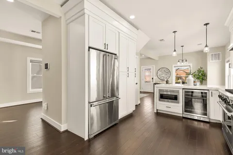 a kitchen with stainless steel appliances a refrigerator a stove and white cabinets