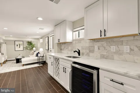 a kitchen with a sink dishwasher stove and white cabinets with wooden floor