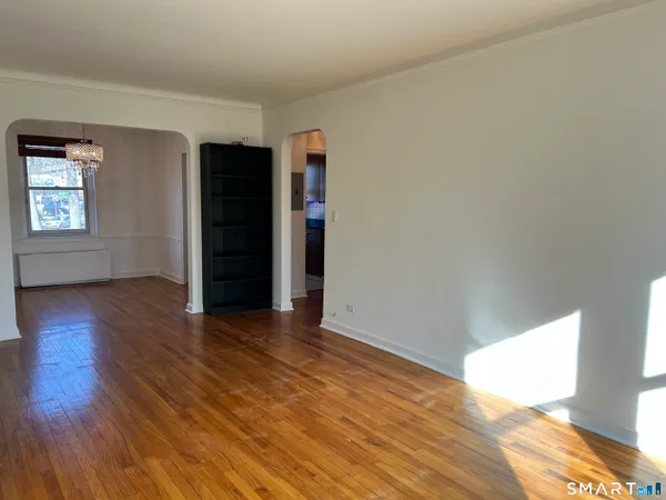 a view of an empty room with wooden floor and closet