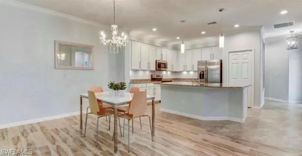 a kitchen with kitchen island a dining table chairs stainless steel appliances and cabinets