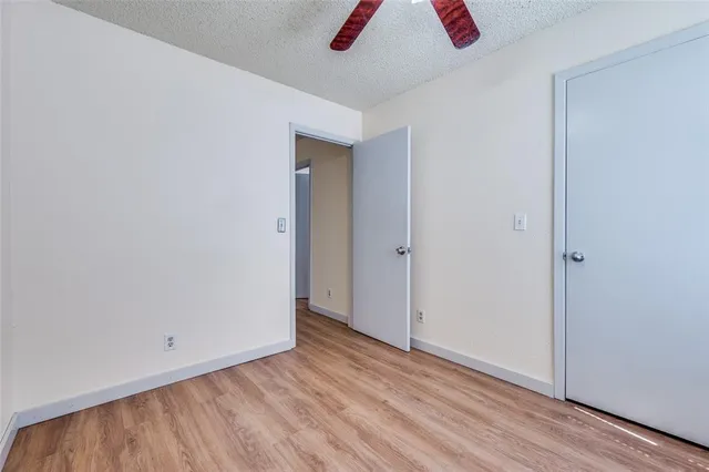 an empty room with wooden floor closet and windows