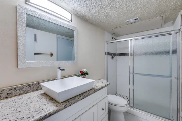 a bathroom with a granite countertop sink toilet and shower