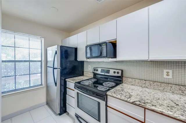 a kitchen with stainless steel appliances granite countertop white cabinets and a stove