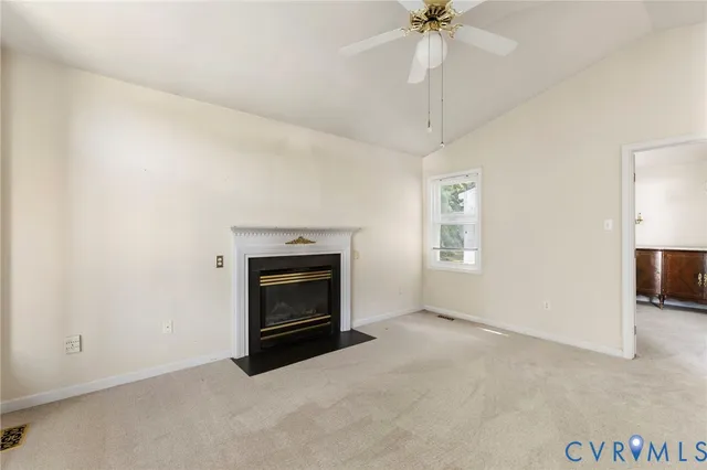 a view of an empty room with a fireplace and a chandelier fan