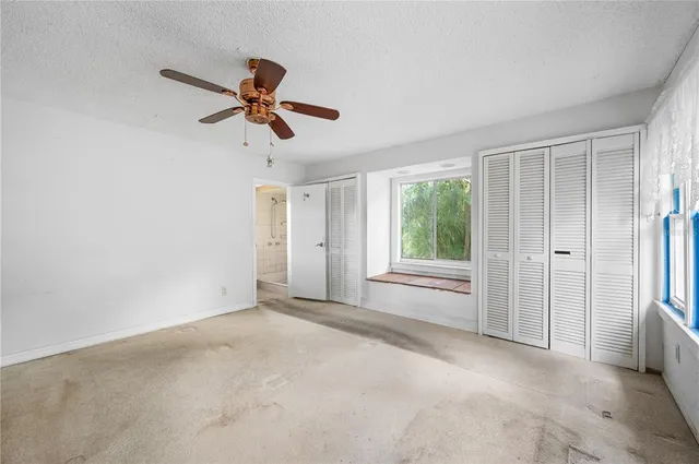 a view of a livingroom with a ceiling fan & windows