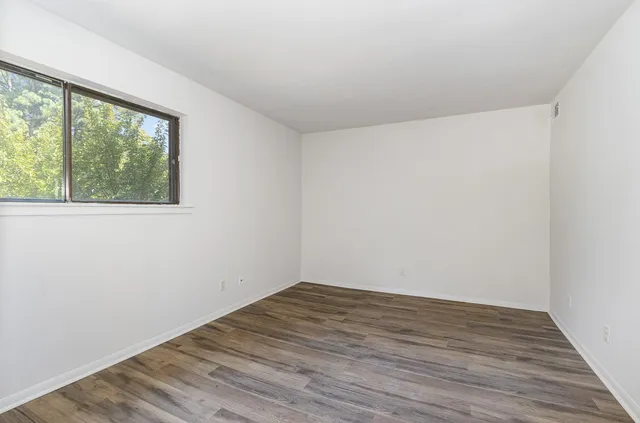 an empty room with wooden floor and windows
