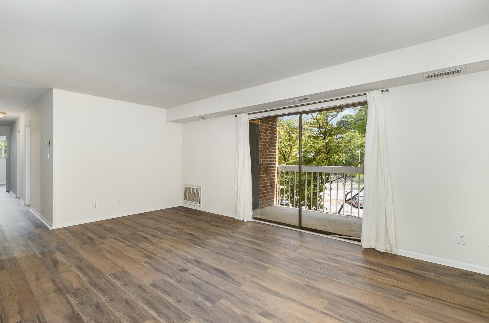 1130 Schaub Drive, Unit C Raleigh, NC 27606 - Photo 5 of 25 a view of an empty room with wooden floor and a window