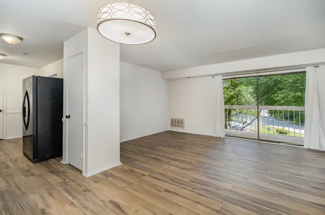 a view of an empty room with wooden floor and a window
