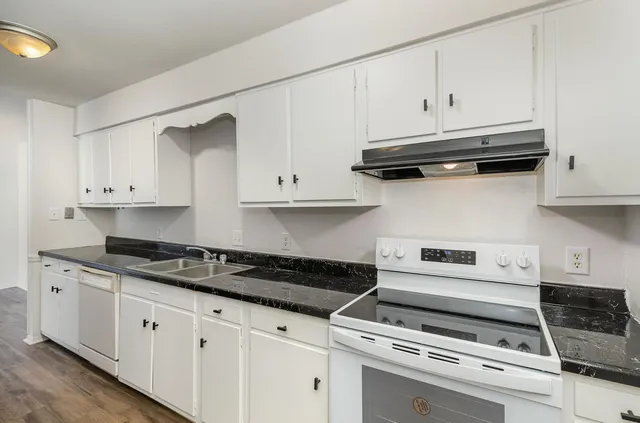 a kitchen with white cabinets and appliances