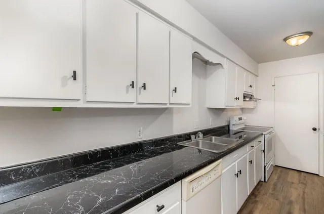 a kitchen with granite countertop white cabinets and a sink