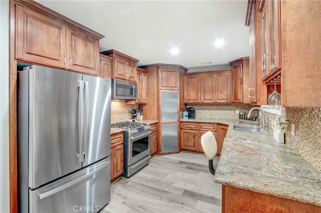 9732 Belmont Drive Riverside, CA 92503 - Photo 6 of 20 a kitchen with stainless steel appliances granite countertop a refrigerator a stove and a sink with wooden floors