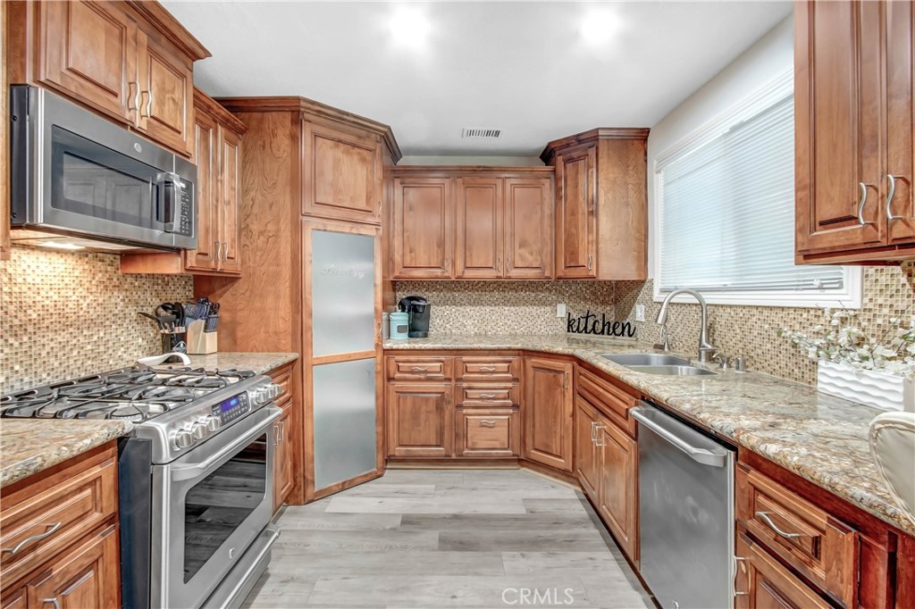 9732 Belmont Drive Riverside, CA 92503 - Photo 7 of 20 a kitchen with stainless steel appliances granite countertop a stove top oven a sink dishwasher and a refrigerator with wooden cabinets
