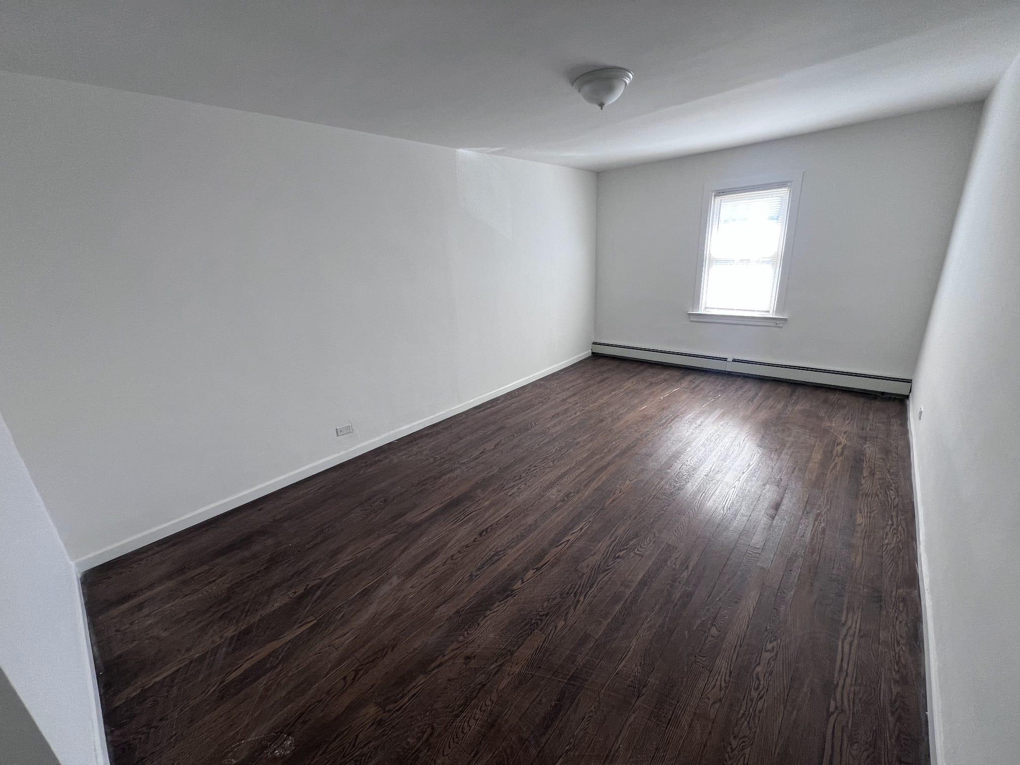 Spare room featuring a baseboard radiator, dark wood finished floors, and baseboards
