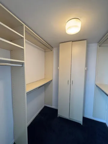 a view of an empty room with wooden floor and closet