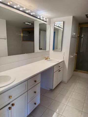 a spacious bathroom with a double vanity sink a mirror and a shower