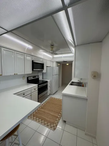 a kitchen with granite countertop a sink a stove top oven and cabinetry