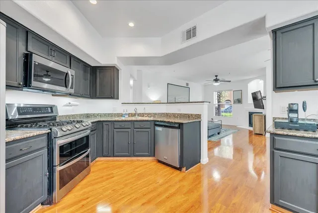 a large kitchen with stainless steel appliances granite countertop a stove top oven a sink dishwasher and cabinets