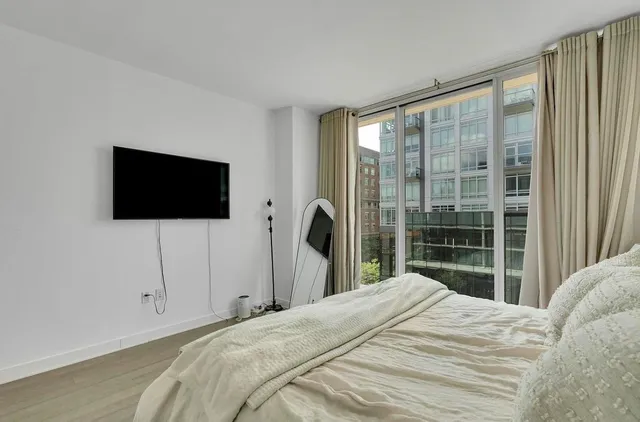 a bedroom with a bed tv and a window