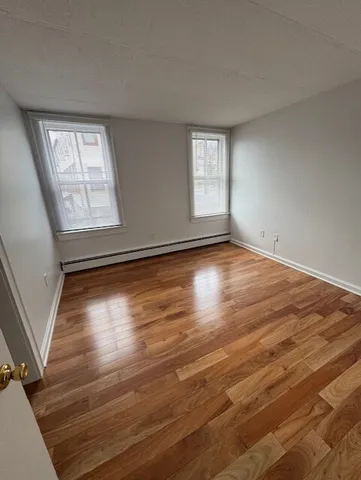 a view of an empty room with wooden floor and window