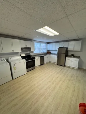 a kitchen with stainless steel appliances granite countertop a stove a sink dishwasher and a refrigerator with wooden floor