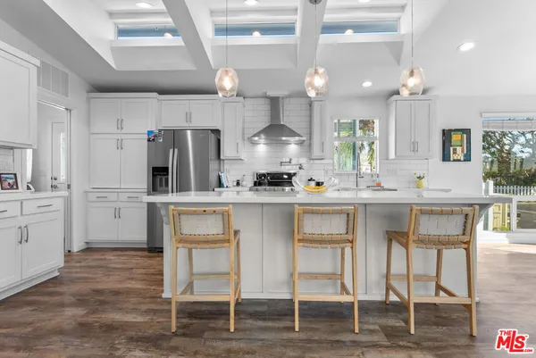 a kitchen with kitchen island granite countertop a table chairs sink and cabinets