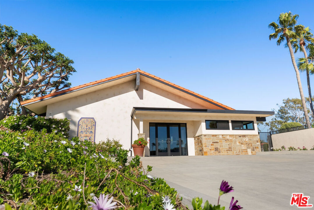 29500 Heathercliff Road, Unit 70 Malibu, CA 90265 - Photo 22 of 38 a view of a white house with large windows and flower plants