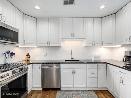 a kitchen with granite countertop white cabinets and stainless steel appliances