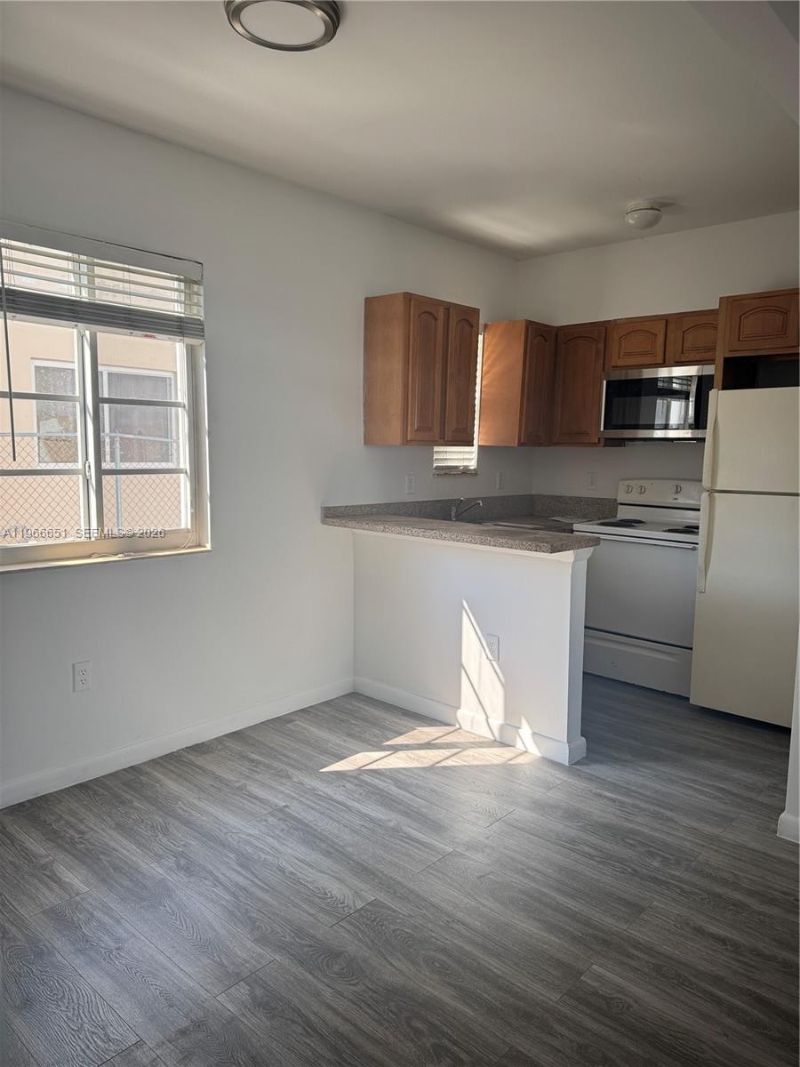 7130 Rue Versailles Drive, Unit 3 Miami Beach, FL 33141 - Photo 4 of 17 a view of kitchen with stainless steel appliances granite countertop a stove a sink and white cabinets with wooden floor