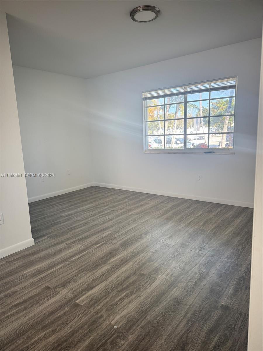 7130 Rue Versailles Drive, Unit 3 Miami Beach, FL 33141 - Photo 5 of 17 wooden floor in an empty room with a window