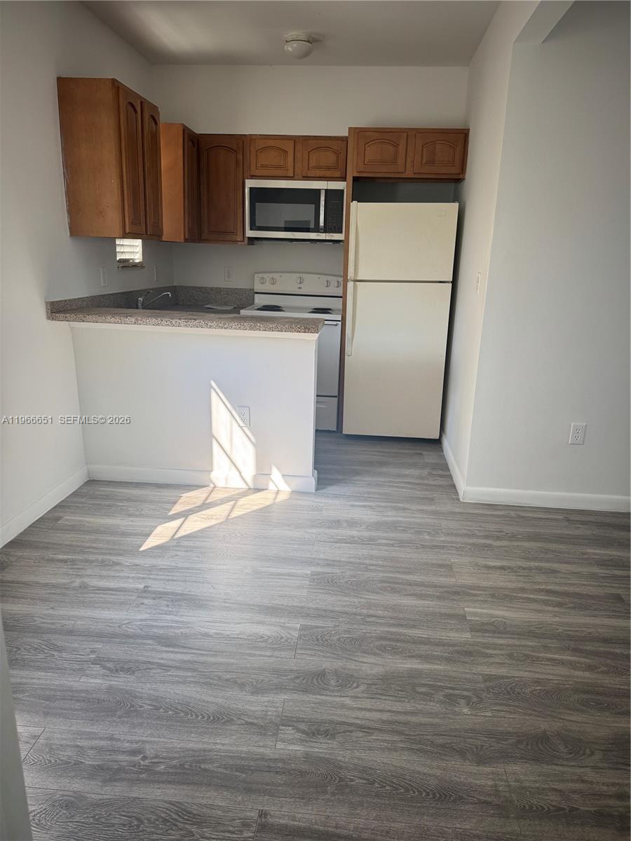 7130 Rue Versailles Drive, Unit 3 Miami Beach, FL 33141 - Photo 6 of 17 a kitchen with stainless steel appliances wooden cabinets and a wooden floor