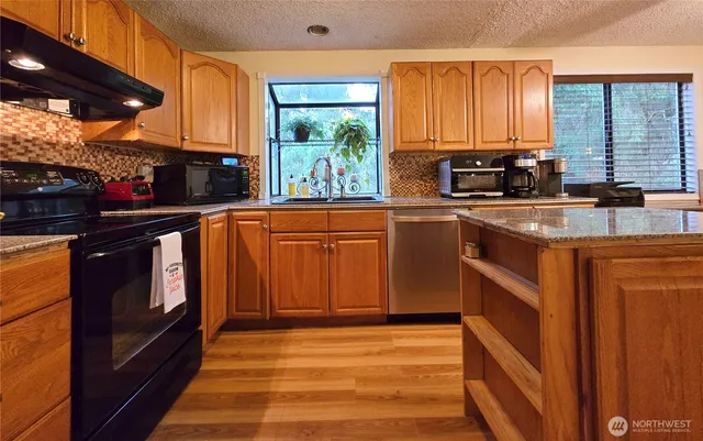 a kitchen with stainless steel appliances granite countertop a stove a sink and a microwave