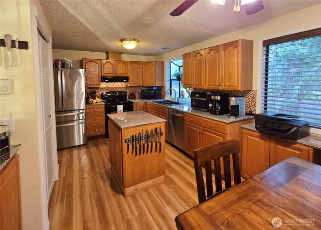 a kitchen with granite countertop a refrigerator stove top oven and sink