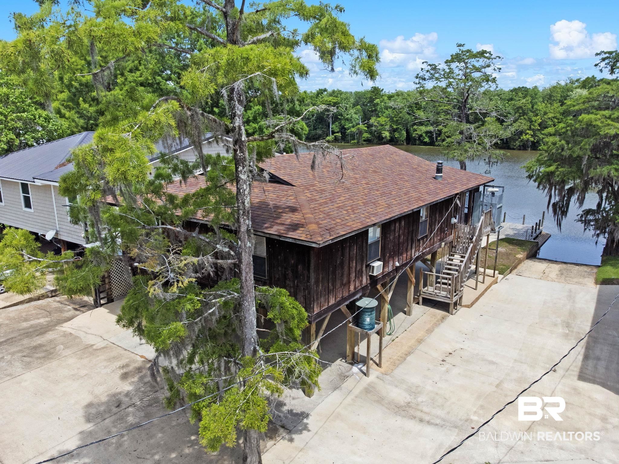 8153 Bryant's Lndg Road Stockton, AL 36579 - Photo 1 of 87 Waterfront property featuring a private boat launch, dock, elevated wood-sided structure, and a brown shingle roof