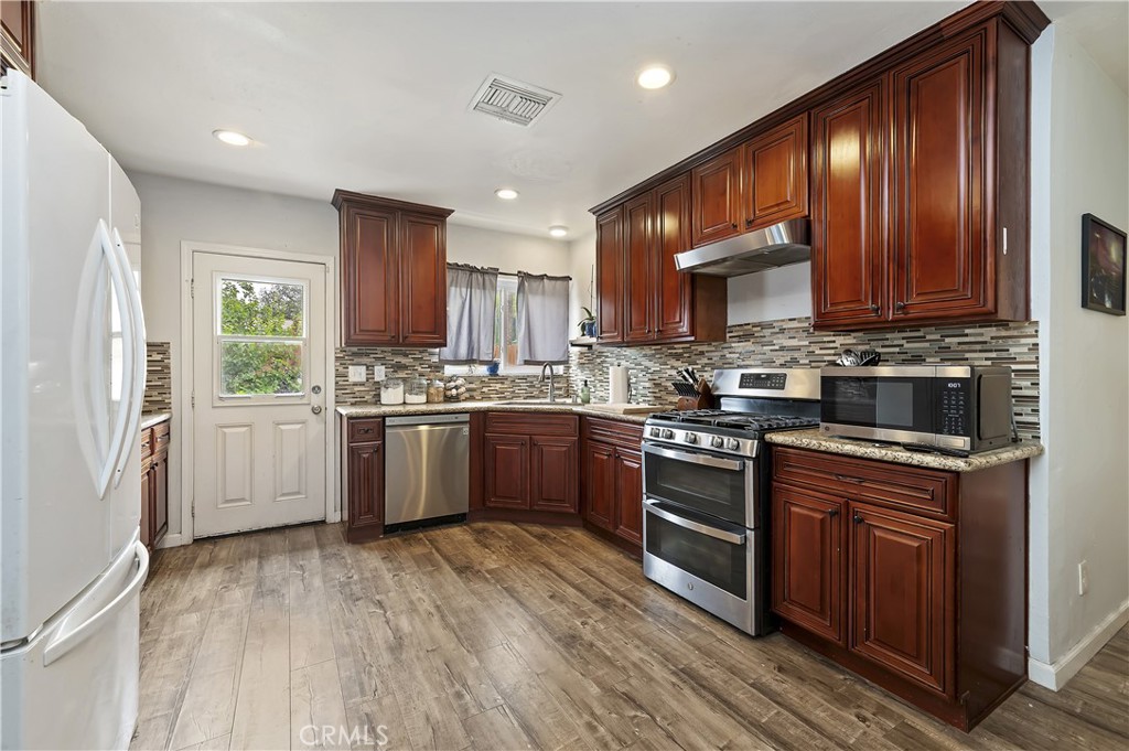 3075 Ronald Street Riverside, CA 92506 - Photo 13 of 30 a kitchen with stainless steel appliances granite countertop wooden cabinets sink and stove top oven
