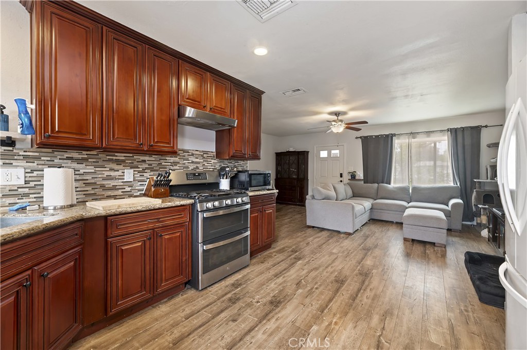 3075 Ronald Street Riverside, CA 92506 - Photo 14 of 30 a kitchen with stainless steel appliances granite countertop wooden floors a stove and a sink