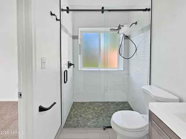 a bathroom with a granite countertop shower a toilet and a sink